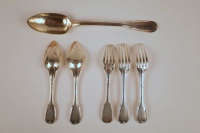 cinq fourchettes et une cuillère sur une table blanche