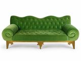 un canapé en velours vert avec des pieds et des accoudoirs en bois