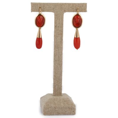 une paire de boucles d'oreilles rouges et dorées posées sur un présentoir