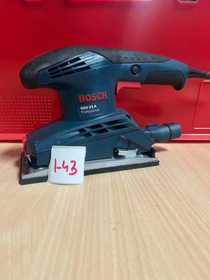 La ponceuse orbitale Bosch est posée sur une table, à côté d'une boîte rouge.