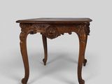 a small wooden table with carved legs and a carved top