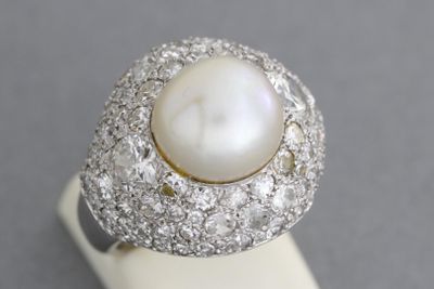 gros plan d'une bague en perles et diamants sur une surface blanche
