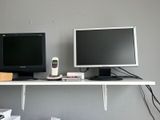 two monitors and a remote control on a desk