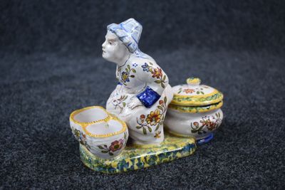 a figurine of a woman sitting on top of a bowl