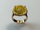 a close up of a gold ring with a coin on it