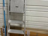 a ladder that is leaning against a wall next to a broom