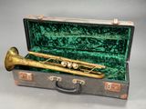 a brass trumpet in a green case on a table