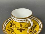 yellow and white coffee cup and saucer with a gold rim