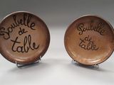 deux assiettes marron portant des inscriptions, posées sur une table