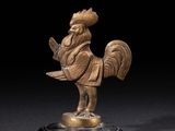 une figurine antique en bronze représentant un coq, posée sur un socle en marbre