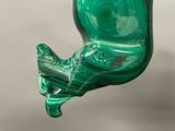 someone is holding a green glass ornament in their hand