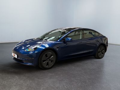 une Tesla Model 3 bleue garée dans une pièce blanche