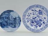 two blue and white plates on display on a table