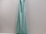 green dress hanging on a white hanger on a gray wall