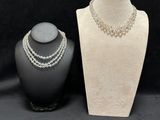 a white mannequin with pearls and a necklace on a black background