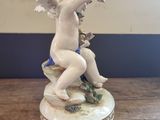 a figurine of a cupid sitting on top of a wooden table
