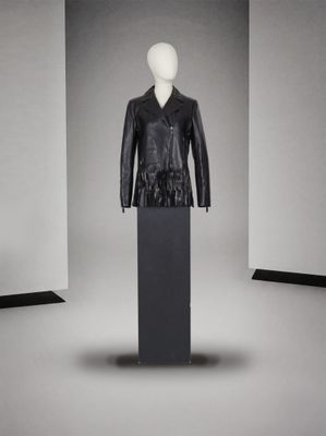 mannequin vêtu d'une veste en cuir noir, posé sur un socle dans une pièce blanche