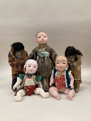 Plusieurs poupées représentant des personnes d'origine asiatique sont disposées en rangée sur un fond blanc.