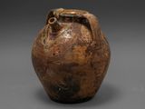 un vieux vase marron posé sur une surface grise
