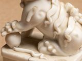 a white statue of a dog with a ball in its mouth