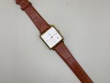 une montre marron avec un cadran blanc posée sur une table