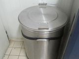 a trash can sitting next to a refrigerator in a kitchen