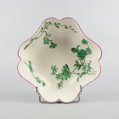 un bol blanc orné de fleurs vertes, posé sur un socle