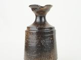 a brown vase that is sitting on a white surface