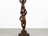 une statue en bronze représentant un garçon tenant un bol, posée sur un socle
