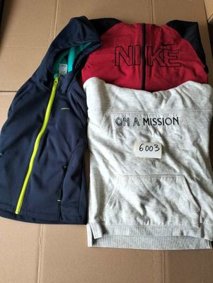 two jackets and a t - shirt are sitting on a cardboard box