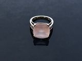 a pink stone ring sitting on top of a black surface
