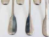 six silver spoons are lined up on a white surface