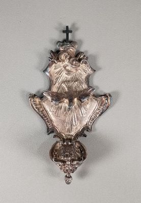 une horloge en argent accrochée au mur, sur laquelle est gravée une croix