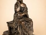 une statue en bronze représentant une femme assise sur un banc