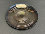 a silver frisbee sitting on a table with a black background