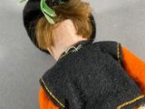a doll that is laying on the floor with a green leaf on it ' s head