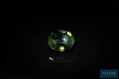 a green tourmaline stone on a black surface