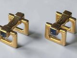 pair of gold tone cufflinks with blue stones on a white surface