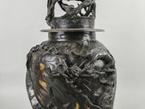 un vase noir surmonté d'un oiseau