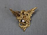 une image représentant une broche plaquée or sur laquelle figure un oiseau sur la tête