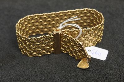 gros plan d'un bracelet en or sur une surface noire