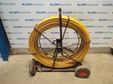 a yellow hose on a cart next to a blue wall