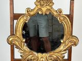 un miroir posé sur un pied, devant lequel se tient un homme