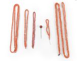 several orange beaded necklaces and a pair of scissors on a white surface