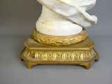a white marble bust of a man on a gold stand