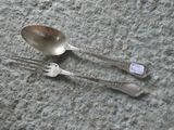 two silver spoons and a fork on the ground