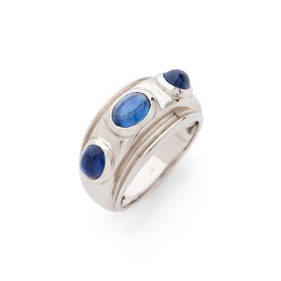 un gros plan d'une bague ornée de pierres bleues sur fond blanc