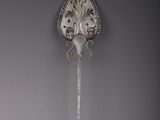 an antique silver spoon with a decorative handle on a gray wall