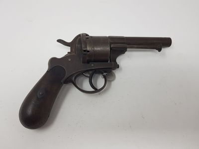 un vieux revolver avec une poignée en bois sur une surface blanche