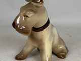 une petite figurine de chien assise sur une surface blanche